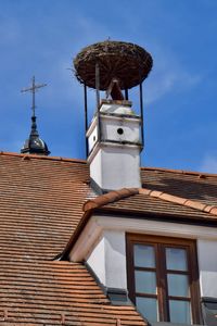 Low angle view of roof of building with stork nest against sky