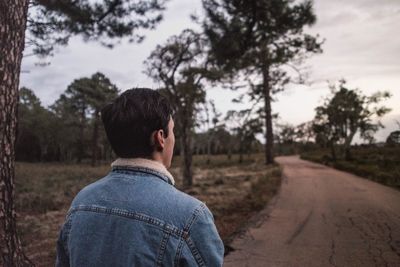 Man on road by trees against sky