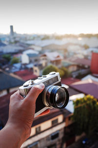 Close-up of hand holding camera against townscape