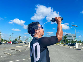 Man standing on road in city against blue sky