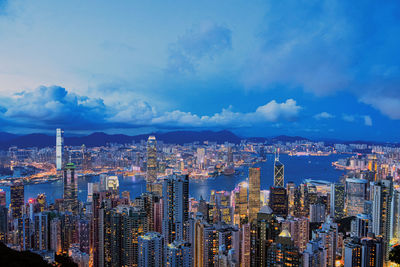 Aerial view of buildings in city against cloudy sky