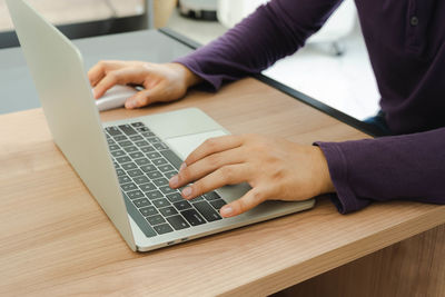 Midsection of man using laptop on table