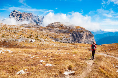 Rear view of hiker walking on mountain against sky