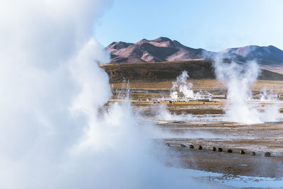 Geyser erupting against mountains