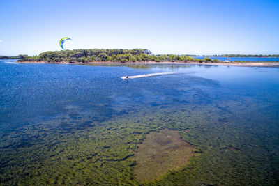 Person kiteboarding in sea against clear sky