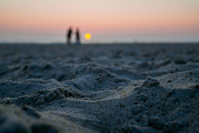 Surface level of beach against sky during sunset