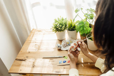 Female painting a modern easter eggs. brushes and paints with flowers and plants. happy easter 