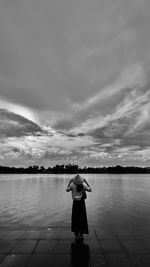 Rear view of woman walking on beach against sky