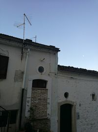 Low angle view of cross on building against clear sky