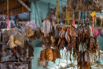 Dried fish tied into several bundles for sale, hanging from above, in a local fish market.