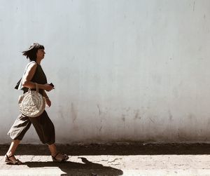 Side view of woman walking against wall