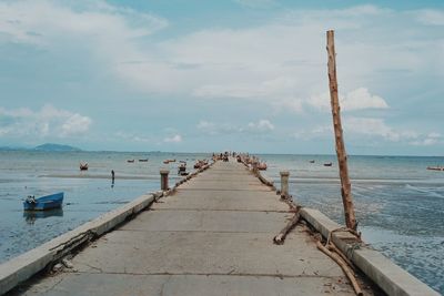 Wooden posts on pier at beach against sky