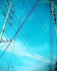 Low angle view of electricity pylon against blue sky