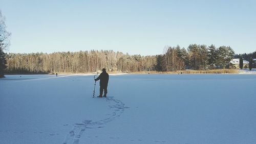 Rear view of man on snowy field against clear sky