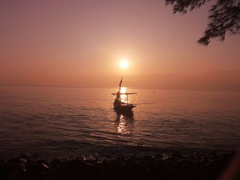 Silhouette sailboat in sea against sky during sunset