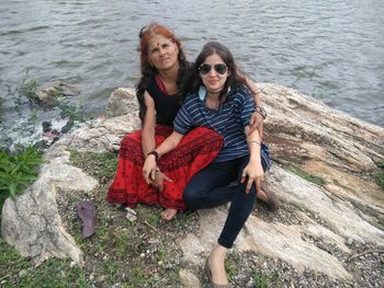 High angle portrait of mother and daughter sitting at riverbank