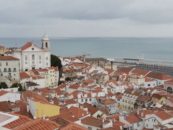 Aerial view of townscape by sea against sky