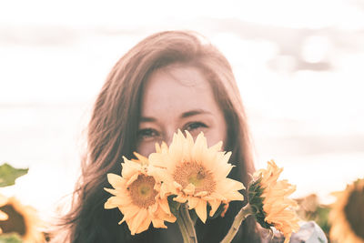 Portrait of beautiful young woman against white flowering plants