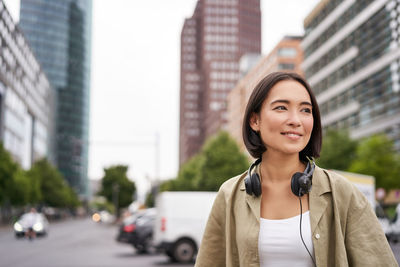 Portrait of young woman standing in city