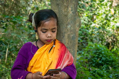 Portrait of young woman standing against trees