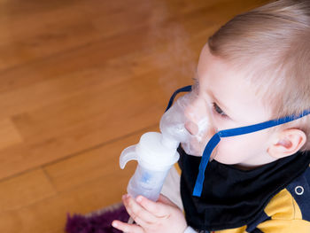Cute boy wearing oxygen mask on parquet floor