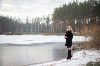 Full length portrait of woman standing by trees against sky