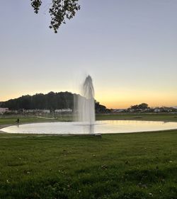 Fountain on field against sky during sunset