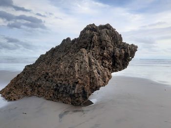 Rock formation on beach against sky