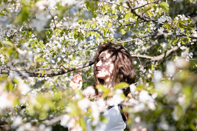 Thoughtful young woman amidst flowering tree