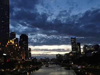 Illuminated cityscape against cloudy sky