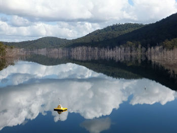 Scenic view of boat in lake against cloudy sky