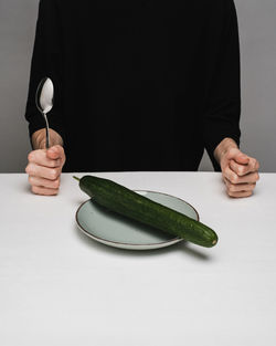 Midsection of person holding ice cream cone against white background