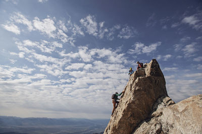 Three rock climbers each the summit of a mountain in tetons, wyoming