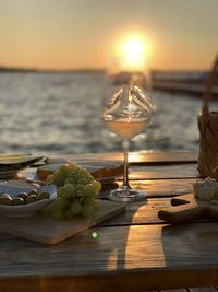 Close-up of fruit on table against sea during sunset