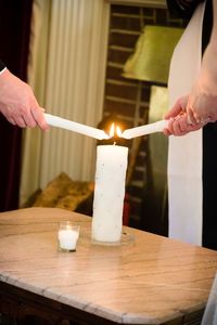 Cropped hands lighting candles on table