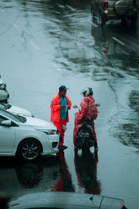 Rear view of man with umbrella on wet road during rainy season