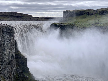 Scenic view of waterfall against sky