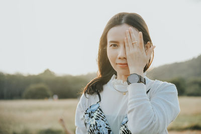 Portrait of smiling mid adult woman covering eye against clear sky