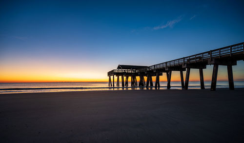 Pier over sea against sky during sunset