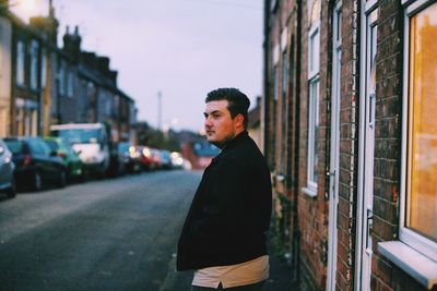 Side view of young man standing in city