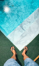 Low section of person standing by swimming pool