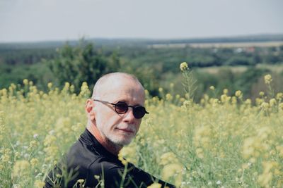 Portrait of man wearing sunglasses sitting amidst plants on land