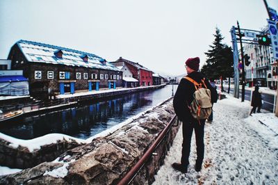 Rear view of man on snow covered canal against sky