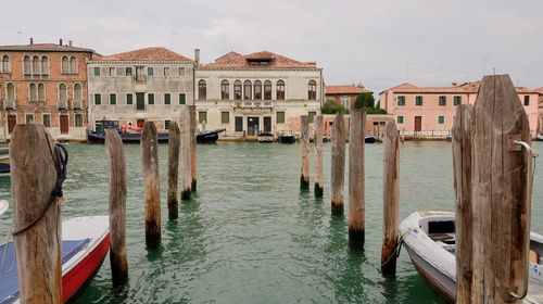 Wooden posts in canal amidst buildings in city