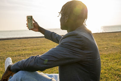 Businessman having video call through smart phone sitting on grass