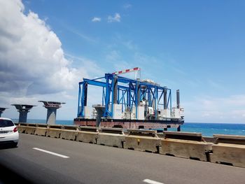 Cranes at harbor against sky