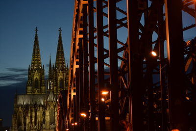 Metallic bridge and cathedral in city at night