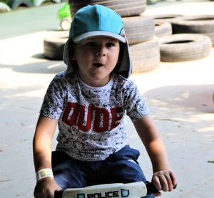 Cute boy wearing cap looking away while playing outdoors