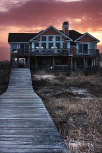 Wooden house on pier amidst buildings against sky during sunset