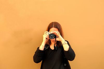 Woman photographing against sky
